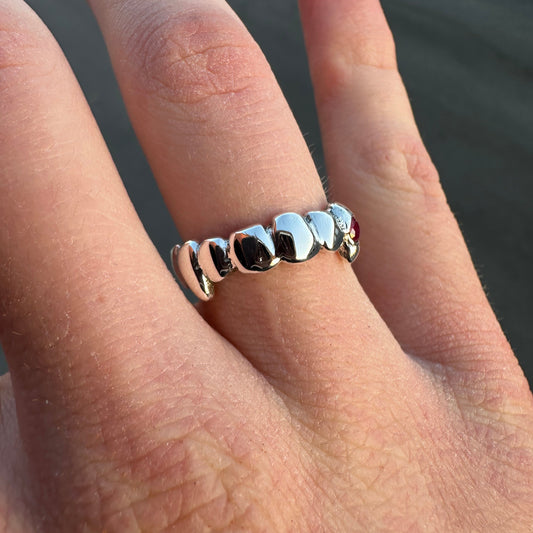 Silver ring with black stones on a finger against a blurred background